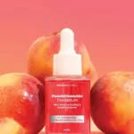 Niacinamide tone-correcting serum bottle surrounded by fresh peaches